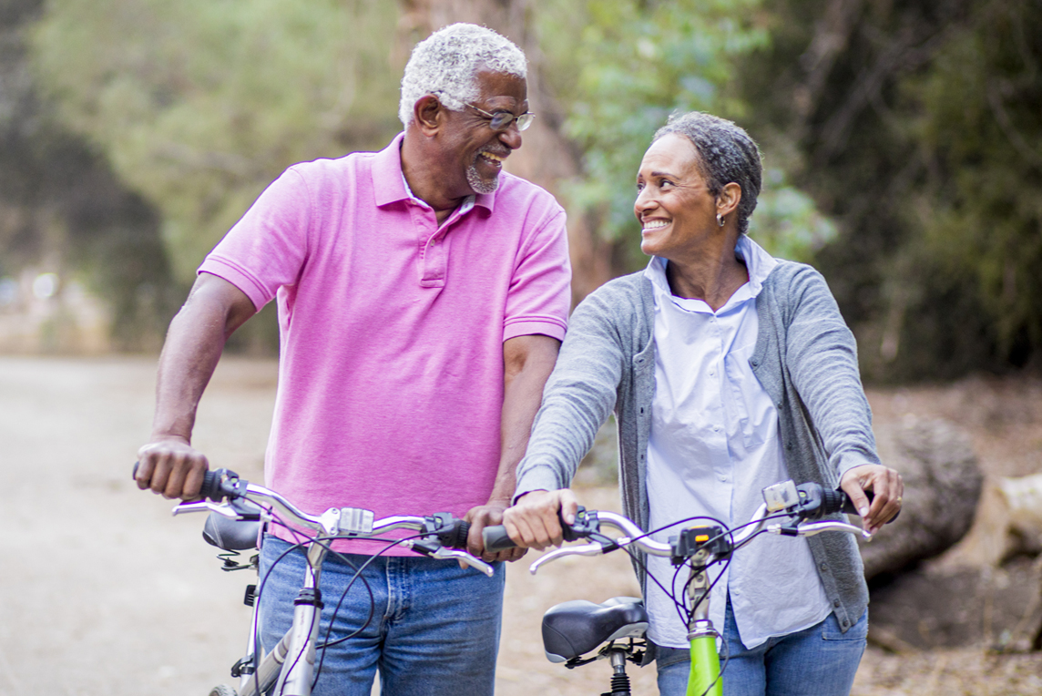 elderly couple walking on trail with bicycles