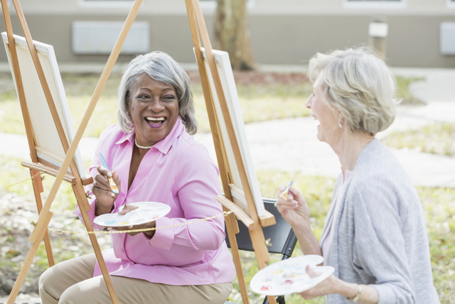 a pair of elderly women taking an art class together and smiling